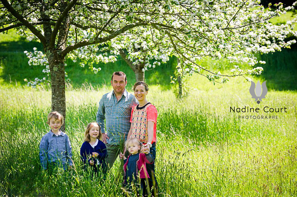 Portrait de famille dans un joli pré fleuri avec des arbres fruités en fleurs