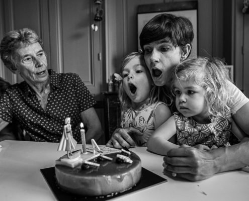 Grand-mère, mère et deux fillettes soufflant ensemble les bougies d'anniversaire, en noir et blanc