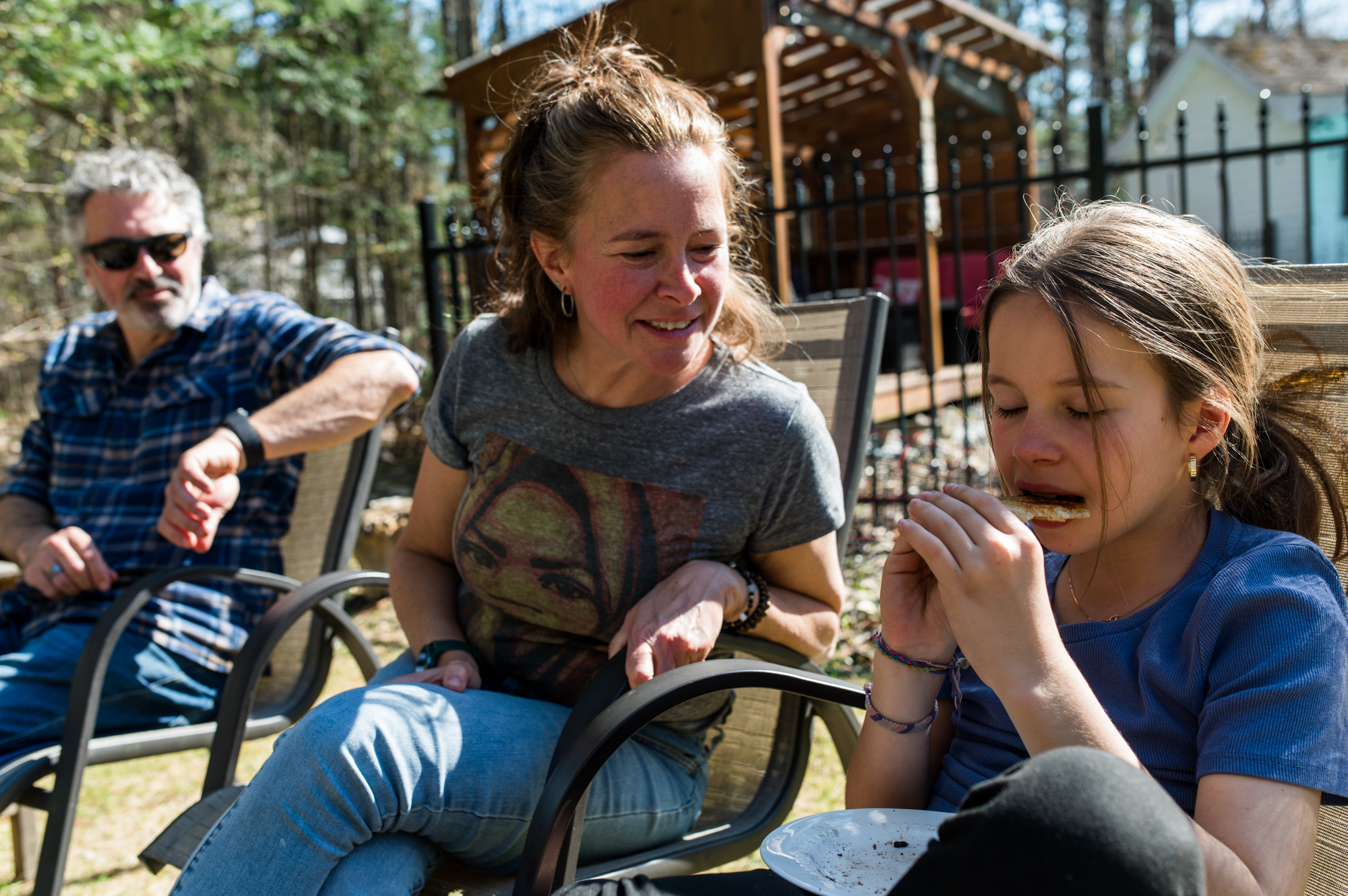 Mère qui rit en regardant sa fille manger une toast grillée au feu de camp dans la cour