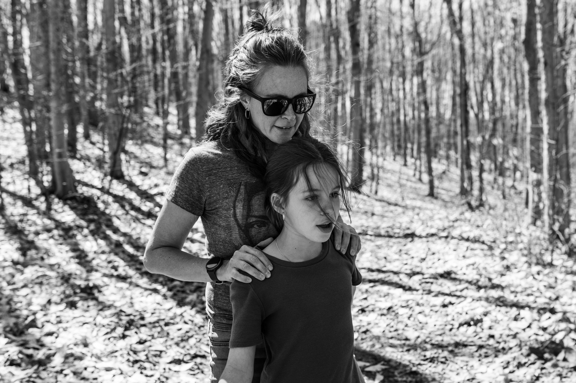 Mère qui enlace tendrement sa fille adolescente lors d'une marche en forêt, en noir et blanc